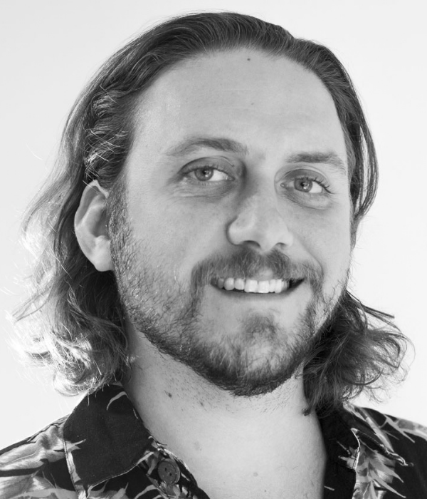 Tonal photo of smiling person with facial hair and shoulder length dark hair.